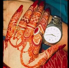 a woman's hand with henna and watch on her left wrist, in red