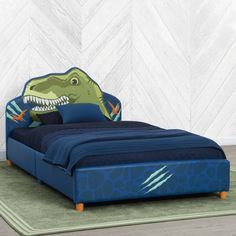 a child's bed with a dinosaur headboard and blue bedspread on it