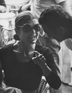 a black and white photo of a woman talking to another woman in front of her