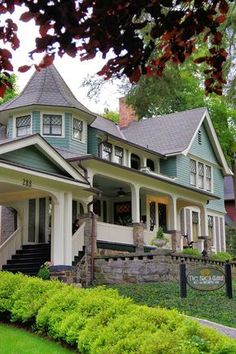 a green and white house sitting on top of a lush green field