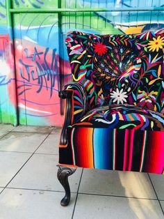 a colorful chair sitting in front of a wall with graffiti on it's walls