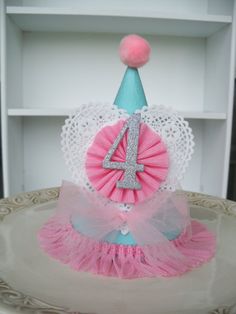 a pink and blue birthday hat with the number four on it sitting on a plate