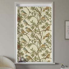 a window with birds on it in front of a white chair and wall behind it