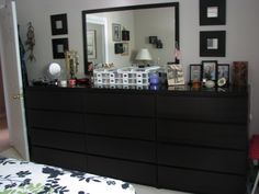 a bedroom with a dresser, mirror and pictures on the wall