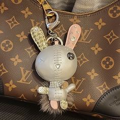 a stuffed animal keychain hanging from a brown louis vuitton handbag