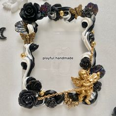 a bracelet with black and white flowers, gold angel charms and other accessories on it