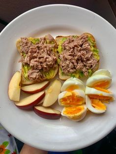 an open faced sandwich on a plate with hard boiled eggs and sliced apple slices next to it