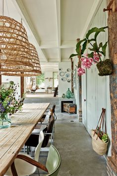 a wooden table sitting next to a white wall with hanging baskets filled with flowers on it