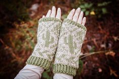 a woman's hands wearing green and white knitted mitts in the woods