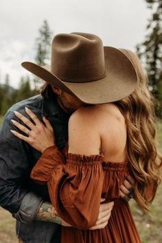 a man in a cowboy hat hugging a woman with long hair wearing an off the shoulder dress