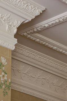 the ceiling is decorated with white flowers and ornate plaster moldings, along with decorative wall hangings