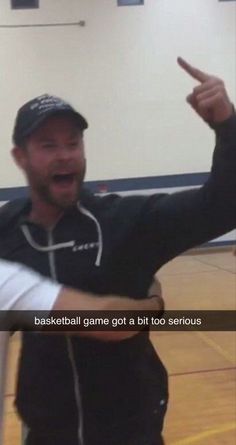 a man pointing at something while standing on a basketball court