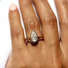 a woman's hand with a diamond ring on top of her finger and the other hand holding an engagement ring