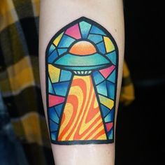 a colorful tattoo on the arm of a person with an alien spaceship in it's center