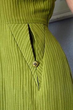 a woman wearing a green dress with a button on it