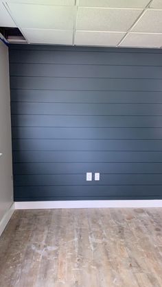 an empty room with hard wood flooring and blue painted garage doors in the background