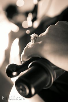 a person holding a wine bottle with a ring on it's finger, in black and white