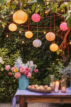 a table topped with vases filled with flowers and paper lanterns