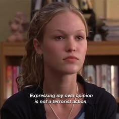 the young woman is talking to someone in front of a book shelf with books on it