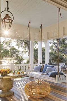 a porch with wooden floors and hanging chairs on the front porch, surrounded by large windows