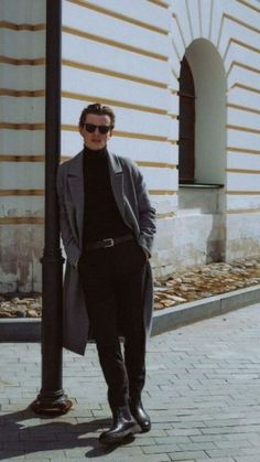 a man standing next to a pole wearing sunglasses