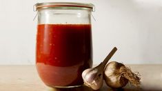 a jar filled with red liquid next to garlic