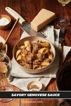 a bowl filled with pasta and meat next to wine glasses