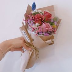 a person holding a bouquet of flowers in their hand with the tag tied to it