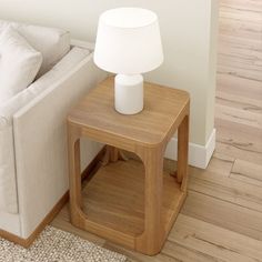 a white couch sitting next to a wooden table with a lamp on top of it