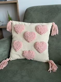 a pillow with pink crocheted hearts and tassels on the back of it