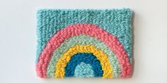 a crocheted square with a rainbow design on the front and bottom, sitting on a white surface