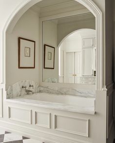 a large bathroom with marble counter tops and white walls, along with framed pictures on the wall