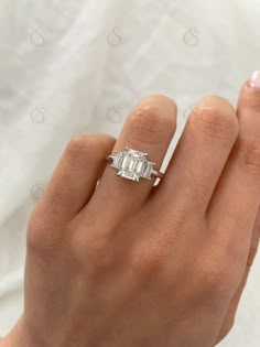 a woman's hand with a diamond ring on top of her finger and the other hand holding an engagement ring