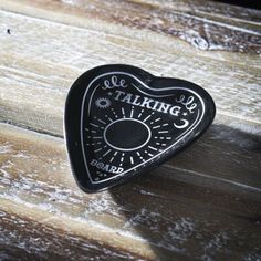 a black heart shaped object sitting on top of a wooden table