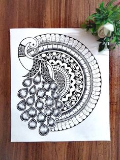 a black and white drawing of a peacock on a piece of paper next to flowers