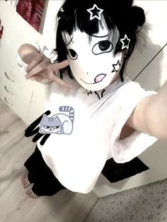 a girl with black hair and white shirt pointing at the camera