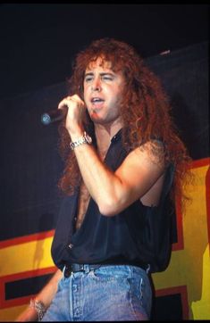 a man with long red hair singing into a microphone