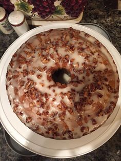 a bundt cake with white icing and pecans on top sitting on a plate