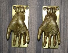 two brass colored metal hand shaped objects on wooden surface