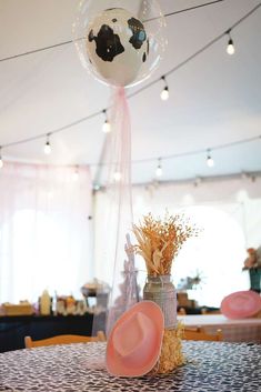 a table topped with a vase filled with flowers next to a ball and cowboy hat