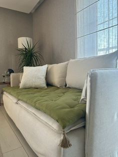 a living room with a white couch and green pillows on it's back end