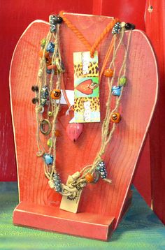 a wooden heart shaped stand with several necklaces on it