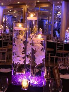 two tall glass vases with flowers and candles