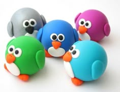 four different colored plastic birds with eyes on each one's head and two are facing the same direction