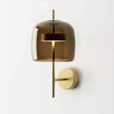 a wall light that is on the side of a white wall with a brown shade