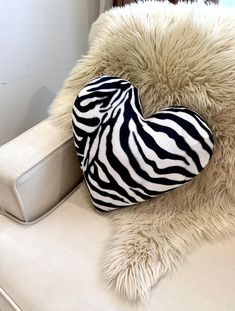 a heart shaped pillow sitting on top of a white couch next to a chair cushion