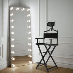 a chair sitting in front of a mirror with lights on it