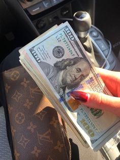 a woman's hand holding money in her car