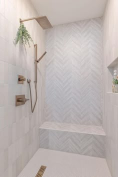 a walk in shower sitting next to a white tiled wall with shelves on each side