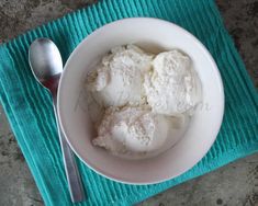 three scoops of ice cream in a white bowl on a turquoise towel with a spoon